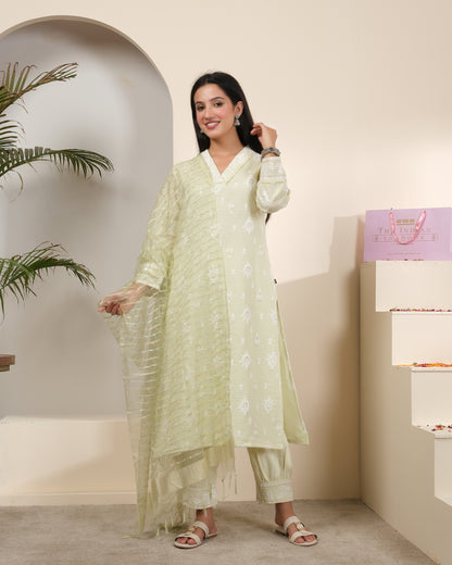 A woman posing in a pastel sage green cotton kurta pant set with a sheer, shimmering striped dupatta featuring tassels