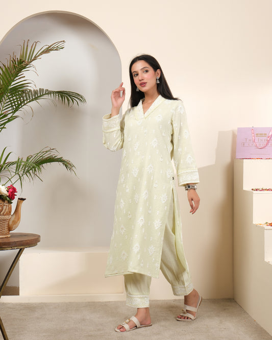 A woman posing in a pastel sage green cotton kurta pant set with a sheer, shimmering striped dupatta featuring tassels