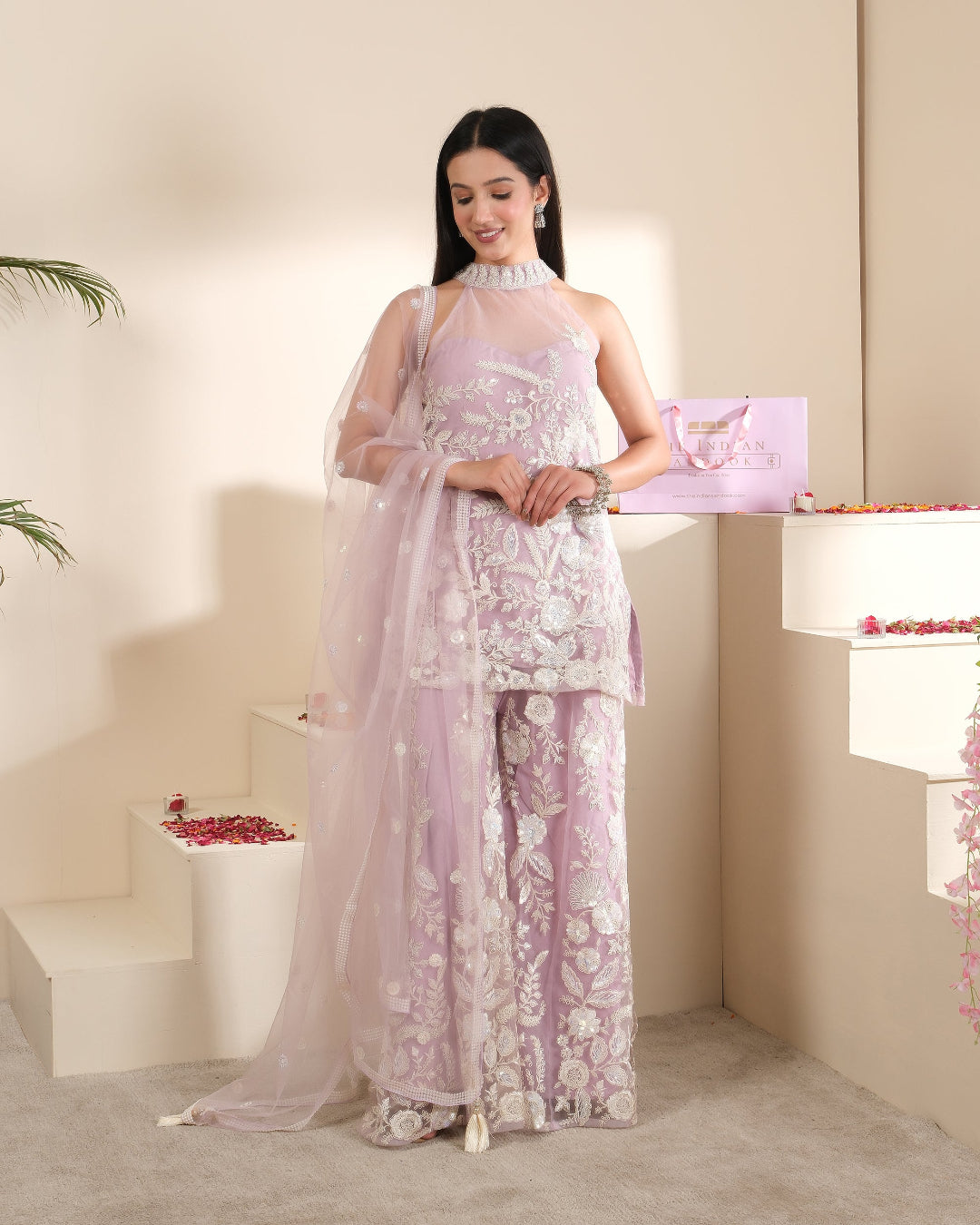 Woman in a light purple floral dress standing in a softly lit room.
